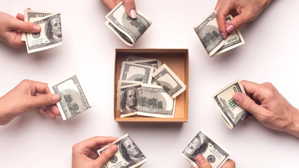 Manos aportando dinero a una caja común