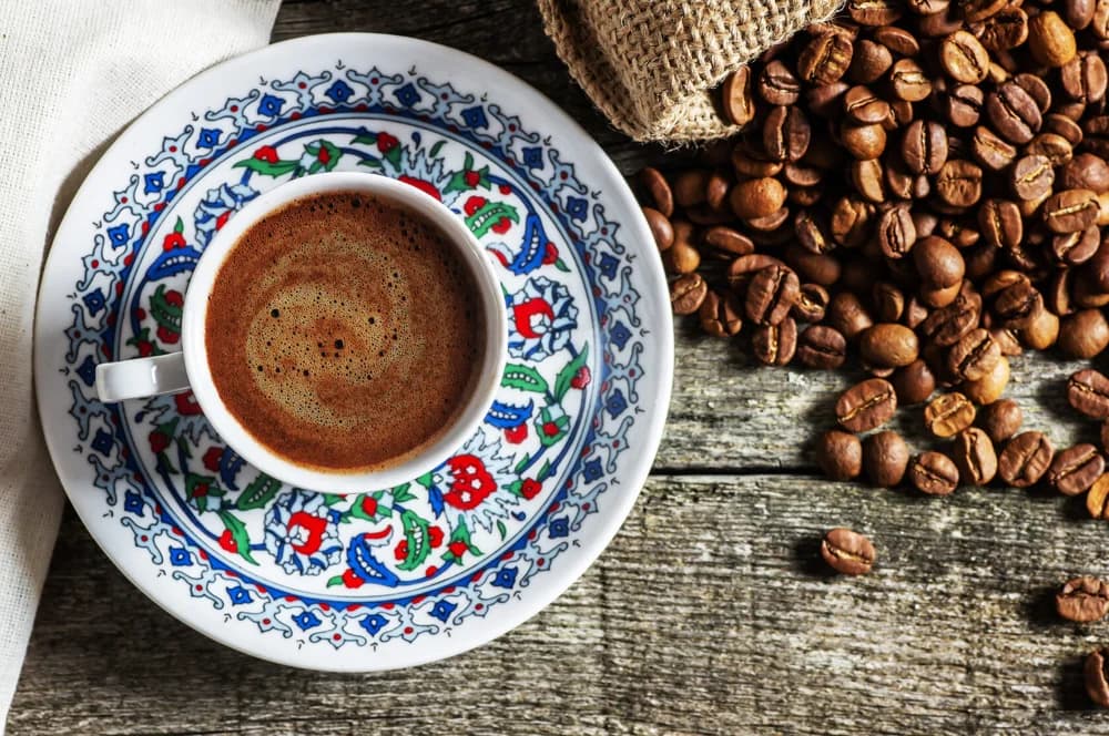 Taza de café junto a granos tostados